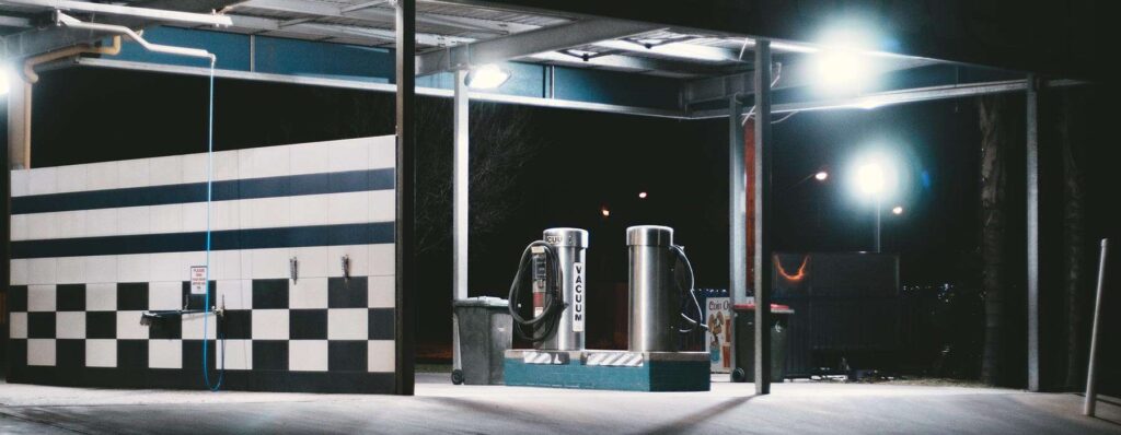 Two stainless steel coffee dispensers at a nighttime gas station.